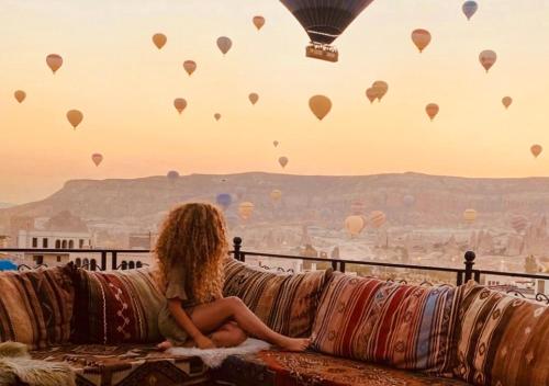 格雷梅Osmanli Cappadocia Hotel的坐在沙发上看热气球的女人