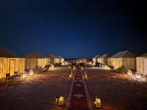 梅尔祖卡Ahlam Luxury Camp的夜晚沙漠中的一排帐篷