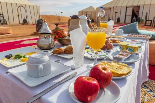 梅尔祖卡Ahlam Luxury Camp的桌上有食物和饮料,苹果