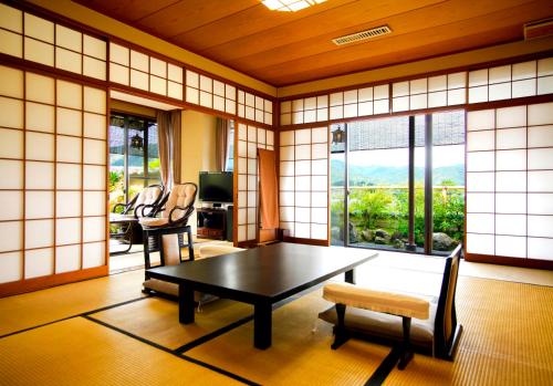 京都Kyoto Arashiyama Onsen Ryokan Togetsutei的客房设有桌椅和窗户。
