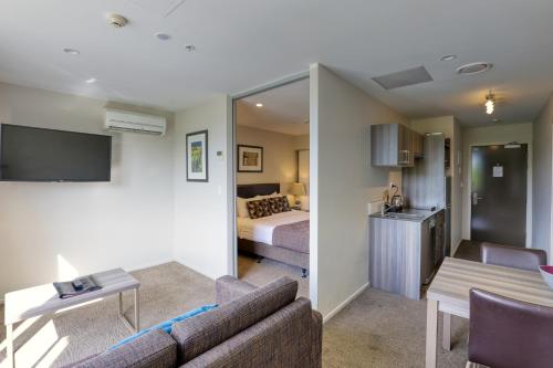 皇后镇Ramada Suites by Wyndham Queenstown Remarkables Park的带沙发的客厅和卧室