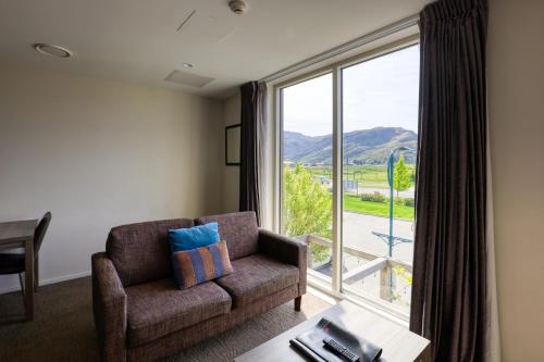 皇后镇Ramada Suites by Wyndham Queenstown Remarkables Park的带沙发和大窗户的客厅