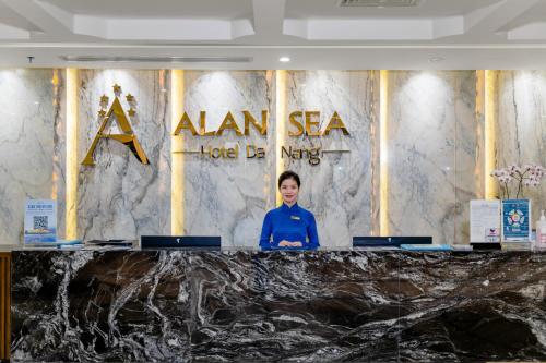 岘港Alan Sea Hotel Danang的站在标牌前的讲台上的女人