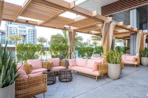迪拜Ultra Luxury Palm Tower with Shared 5 Star Hotel Facilities的一座庭院,里面设有粉红色的椅子和植物