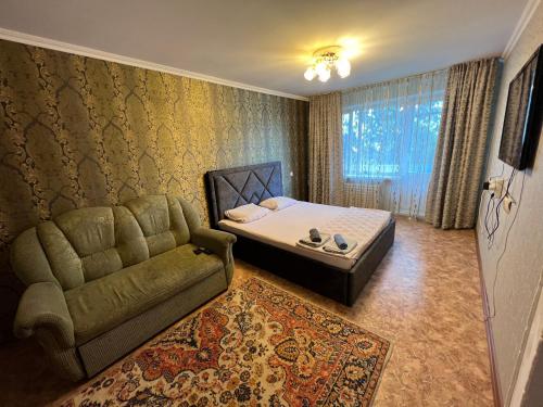 巴甫洛达尔Стандарт Камзина 74 г. Павлодар的一间卧室配有一张床、一张沙发和一个窗口