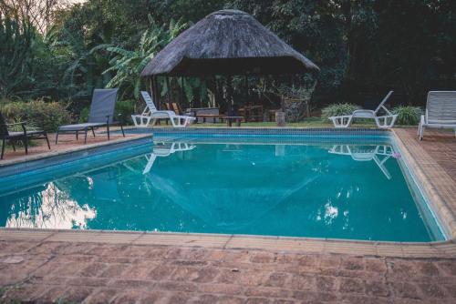 白河Thokozani Lodge的一个带椅子的游泳池和一个凉亭