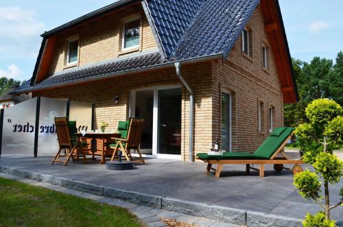 卡尔斯哈根Ferienhaus Wellenbrecher的房屋前设有带桌椅的天井。