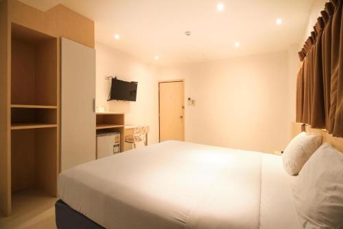 曼谷十星酒店的卧室配有白色的床和电视。