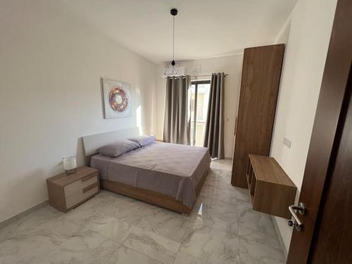 泽布季Gozo - 3 Bedroom - Brand New的一间卧室配有一张床、一个梳妆台和一扇窗户。