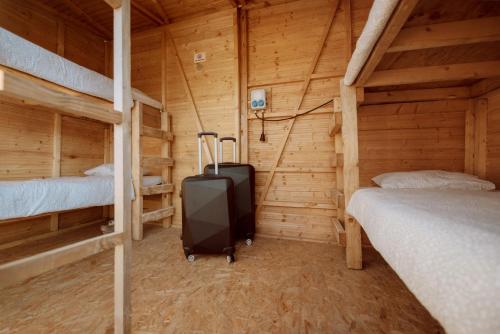 施皮尔贝格Event Lodge Camping Spielberg的一间小屋内带两张床和行李箱的房间