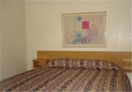 梅萨科罗那汽车旅馆套房的卧室内的一张床铺,墙上挂着一幅画