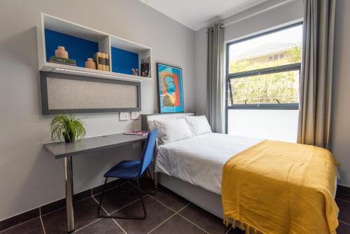 开普敦CampusKey Cape Town的一间卧室配有一张床、一张书桌和一个窗户。