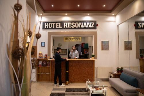 维也纳Hotel Resonanz Vienna的站在酒店前台柜台上的男人
