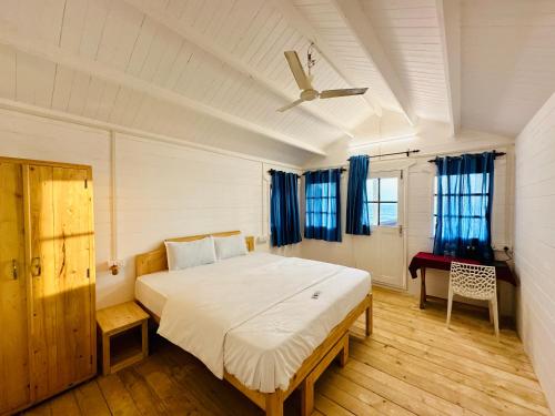 帕罗林Cocos Beach Resort的一间卧室配有一张带蓝色窗帘的大床