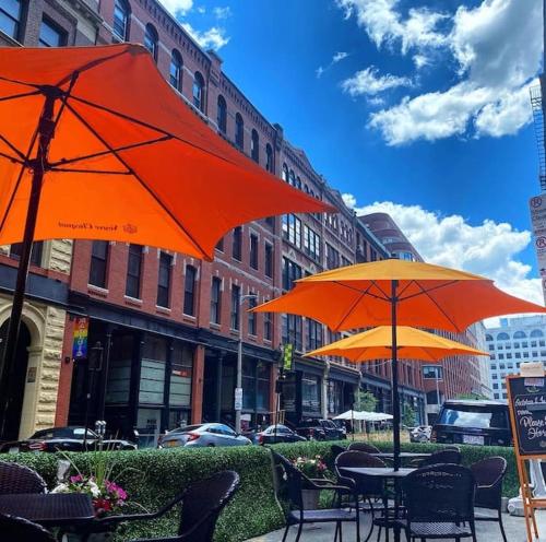 波士顿Beach Street Loft的两张桌子,带橘子伞,位于城市街道上