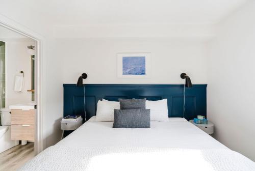 坎莫尔Mount Rundle Hideaway with Heated Pool & Hot Tub and allows Pets的一间卧室配有蓝色床头板和白色的床
