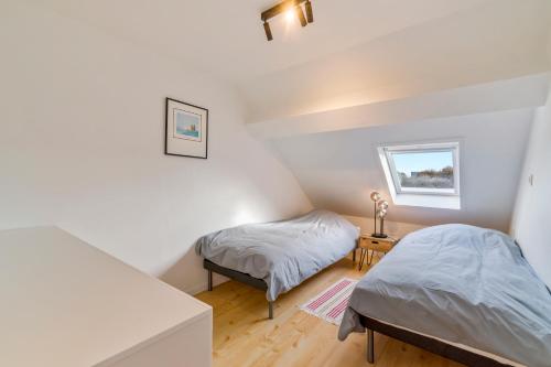奥斯坦德Duinenhuisje的配有白色墙壁和木地板的客房内的两张床