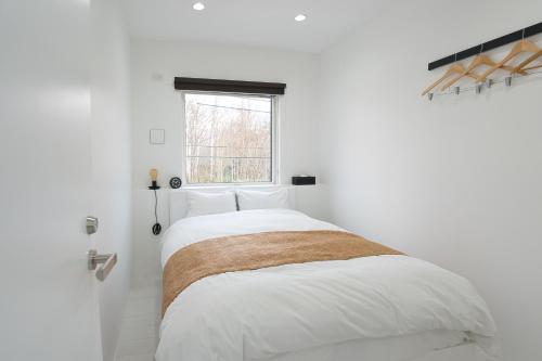 二世古NISEKO EPIC HOUSE的白色的卧室设有一张大床和一个窗户
