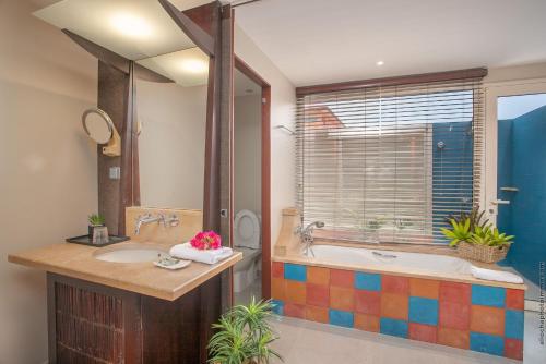 勒弗朗索瓦Villa Maorie 1 chambre avec piscine privée的一间带两个盥洗盆、浴缸和窗户的浴室