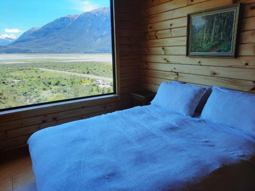 CassArthur's Pass Ecolodge的一间卧室设有一张床和一个大窗户