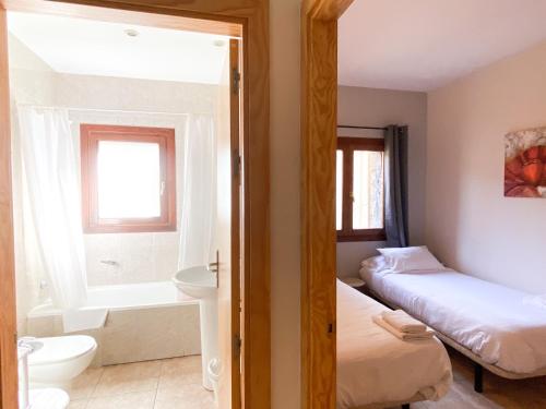 卡尼略Disfruta De La Naturaleza - Vistas al Rio - Luz Natural - 6pax的客房设有两张床和一间带浴缸的浴室。