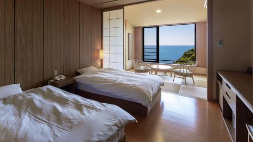 那智胜浦町Kyukamura Nanki-Katsuura的酒店客房设有两张床和一个阳台。