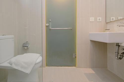 三宝垄KHAS Semarang Hotel的浴室设有玻璃淋浴间,位于水槽旁边