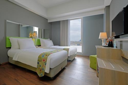 三宝垄KHAS Semarang Hotel的酒店客房设有两张床和一台平面电视。