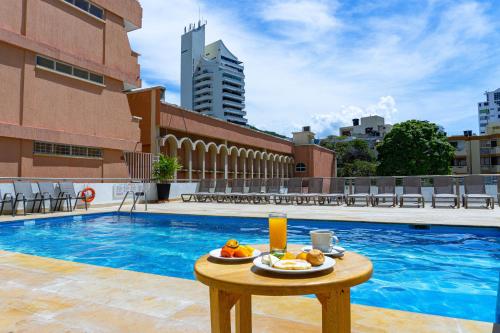 圣玛尔塔Hotel Arhuaco Rodadero的游泳池旁的餐桌上放着食物