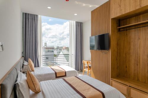 Buôn EnaoKhang Hy Hotel的酒店客房设有两张床和窗户。