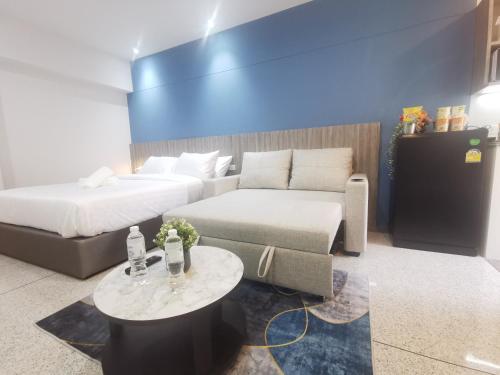 曼谷ABC@48 Hotel & Service Apartment的客房设有两张床、一张沙发和一张桌子。