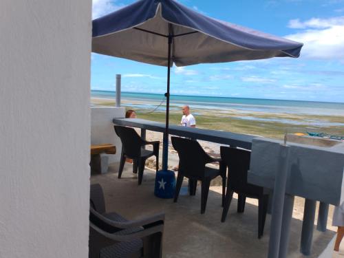 DaanbantayanLittle Sanity Beach house的一位坐在桌子上,在海滩上拿着一把遮阳伞的人