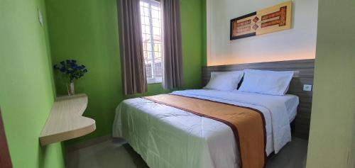 TanjungredepREG GUESTHOUSE的绿色卧室配有床和椅子