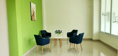 TanjungredepREG GUESTHOUSE的一间设有三把椅子和一张花瓶桌子的房间