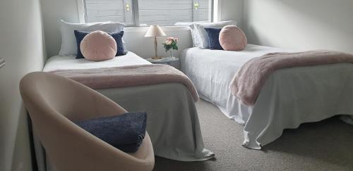 坎布里奇Cambridge Retreat的一间卧室设有两张床、一把椅子和一个窗户。