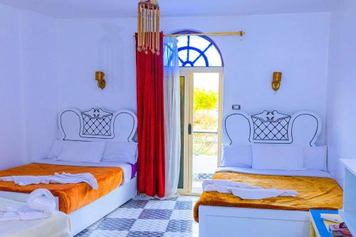 阿斯旺Onaty Ka Guest House的一间卧室设有两张床,并设有一个通往庭院的门。