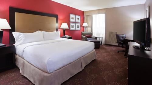 厄兰格辛辛那提机场假日酒店的酒店客房设有一张白色大床和红色的墙壁。