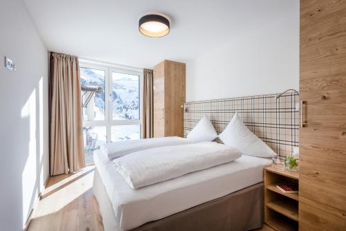 库哈台All-Suite Resort Kühtai的卧室配有一张大白色床和窗户