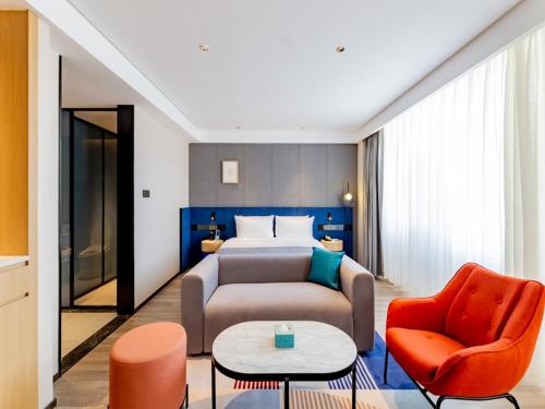 呼和浩特呼和浩特新城区摩尔城兰欧尚品酒店的酒店客房配有一张床、一张沙发和椅子。