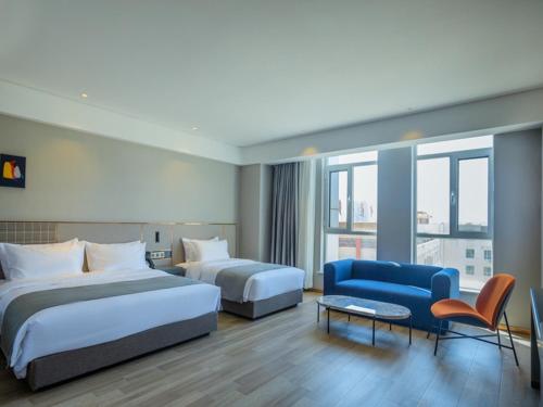 Jiangoushan尚品酒店中宁为民城市广场兰欧的酒店客房,设有两张床和一张蓝色的沙发
