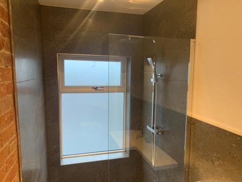 奥萨格Alsager Town Centre Apartment的浴室内设有一个窗户和玻璃淋浴间