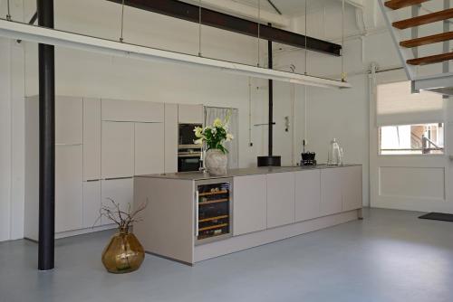 迪伦B&B aan de Koningsmuur的厨房配有白色橱柜和花瓶