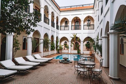 马拉喀什马拉喀什艾奎特酒店的一座带椅子的庭院和一座位于大楼内的游泳池