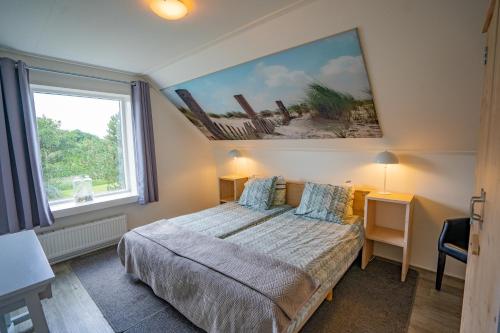 德科赫De Ruige Hoogte的卧室配有一张床,墙上挂有绘画作品