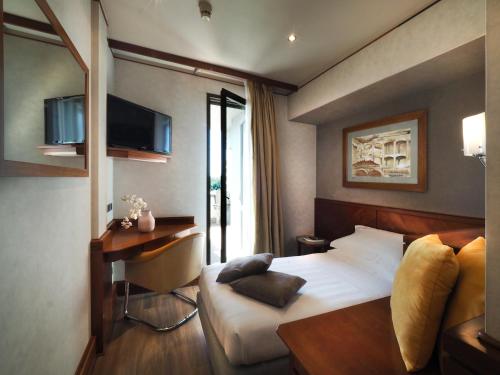 佩鲁贾伯露贾公园酒店的一间卧室配有一张床、一张书桌和一台电视