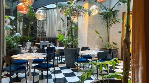 圣地亚哥Hotel Magnolia Santiago的一间设有桌椅和盆栽的餐厅