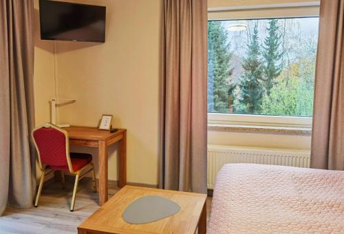 哈茨山区黑尔茨贝格AM BERG Hotel的酒店客房设有一张桌子、一张床和一个窗户。