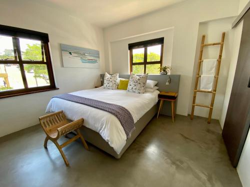 普利登堡湾Stay On Main Plett - Contemporary 2-Bedroom Apartment的一间卧室设有一张大床和两个窗户。