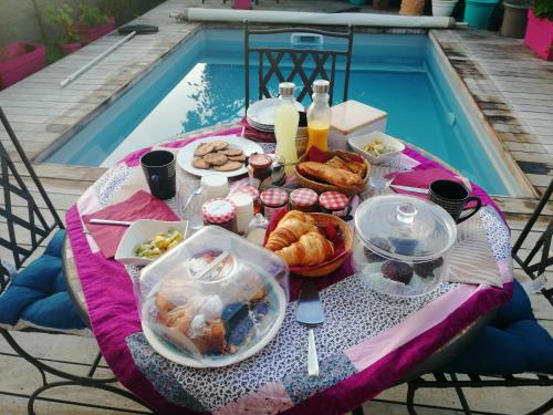 滨海萨纳里L'Ecrin d'Azur的一张桌子,旁边是游泳池,摆放着食物和饮料