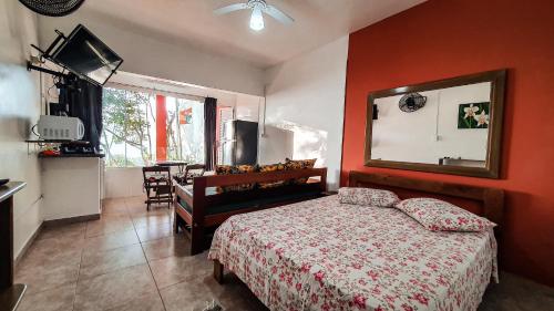 乌巴图巴Pousada Ubatuba do Alto的卧室设有红色的墙壁、一张床和一张桌子